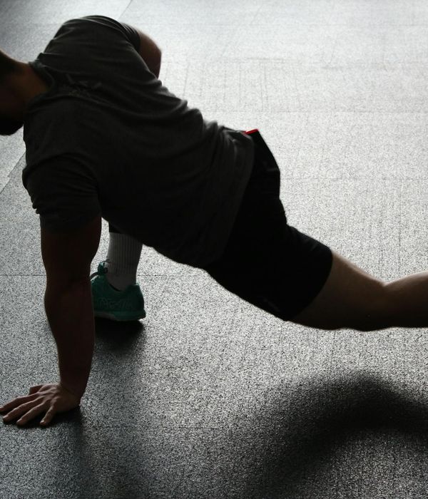 Man performing a core strength exercise in a dark gym setting.